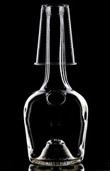 A glass bottle, a plastic cup is put on the neck, on a dark background, wallpaper.