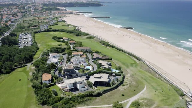 Aerial views of the french city biarritz in the south of France. The drone flys over the atlantic and is overlooking the scenic coast and shows tourist enjoy the beach of the spa town.