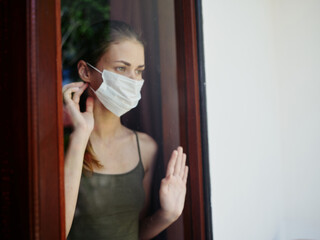 woman looking out the window wearing a lockdown medical mask lockdown