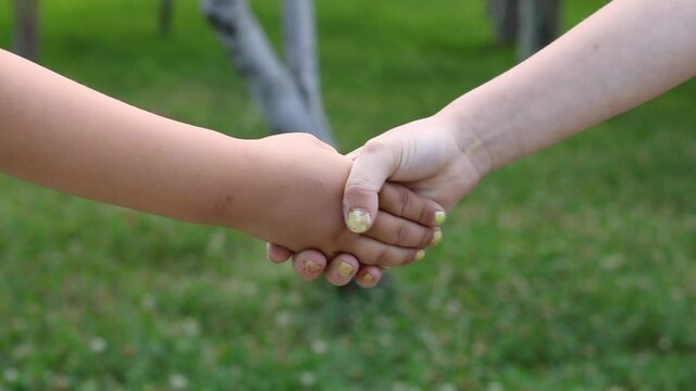 Kids shake hands in the park, blurred backround