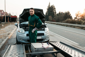 Road assistant worker in towing service trying to start car engine with jump starter and energy...