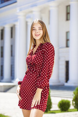 Portrait of a young beautiful blonde woman in a summer burgundy dress