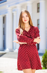 Portrait of a young beautiful blonde woman in a summer burgundy dress