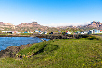 Small coast village at the foot of towering mountains in Iceland on a clear summer day