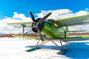An old classic airplane. The biplane stands in the snow on skis in winter against the sky -...