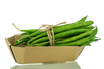 Several ripe green beans in a plate made of paper, close-up, isolated on white.