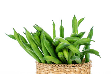 Several ripe pods of green beans in a bowl of straw, close-up, isolated on white.