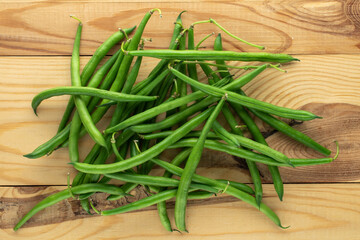 Several organic ripe green beans on a wooden table, close-up, top view.