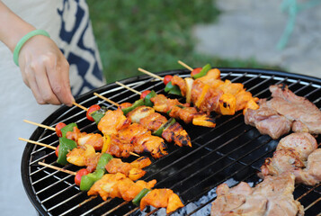 Closeup of  chicken barbecue on gridiron with woman's hand.