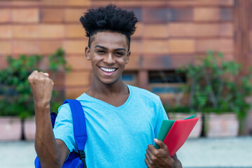 Successful cheering afro american male student with backpack and paperwork