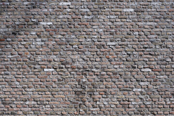 Old grunge brick stone wall made with baked rectangular and square bricks. Shadows of branches fall on the wall