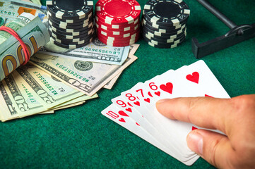 Player points with his finger at a winning straight flush combination in a poker game on a table...