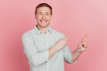 Portrait of nice attractive guy indicate forefinger empty space shiny smile on pink background