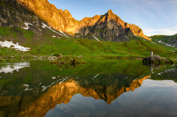 peak of Hochstollen with reflection in alpine lake near Melchseefrutt at sunrise in the swiss alps