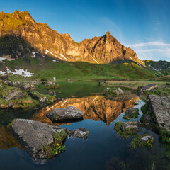 peak of Hochstollen with reflection in alpine lake near Melchseefrutt at sunrise in the swiss alps
