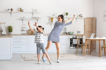 Young woman and her little son dancing in kitchen