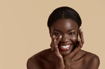 Portrait close up of beautiful african girl. Joyful young woman touch her clean face and looking at...