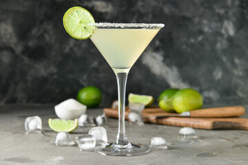Glass with tasty daiquiri cocktail and ice cubes on grey background