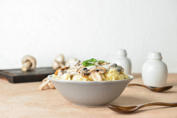 Bowl with tasty mashed potatoes and mushrooms on table
