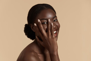 Portrait close up of beautiful african girl. Happy young woman touch her clean face and looking at...