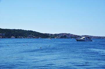 Fototapeta na wymiar Panorama of the sea strait and coastline. The pleasure boat sails on the calm sea.