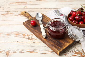 Jar of tasty cherry jam on wooden background