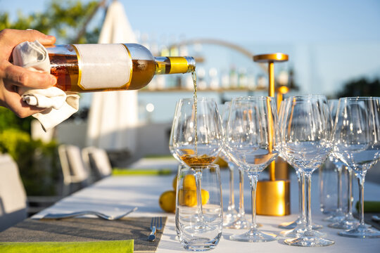 Waiter poiring wine in a glass at outdoor high cuisine restaurant