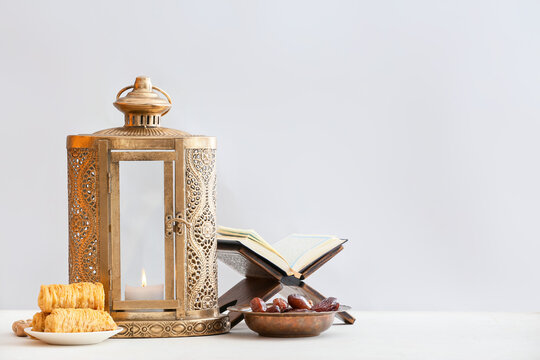 Muslim lantern with Quran and Turkish sweets on light background