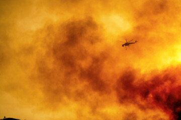 helicopter pours water on a wildfire near the of Ancient Olympia