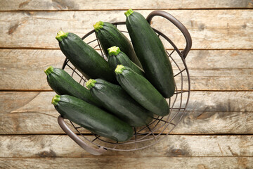 Basket with fresh zucchini squashes on wooden background
