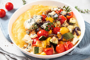 Polenta with stewed vegetables and herbs in a bowl. Polenta with tomatoes, peppers, zucchini,...