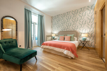 bedroom with king size bed with green velvet upholstered chaise longue seat, wooden floorboards in...
