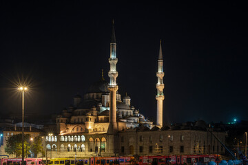 Fototapeta na wymiar Night and long exposure image of the new Muslim Eminonu Mosque in the Golden Horn of Istanbul with the metro passing underneath and the photo taken from the Galata Bridge
