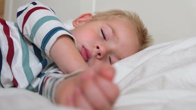 Sleeping Child in Bed. Cute Little Kid Sleeps Sweetly on Cozy White Blanket on its Side. 2 Years Old Child Sleeping in Crib. Face Close-up. Young Boy Lying in Bed on Pillow during the Day Sleep, 4K
