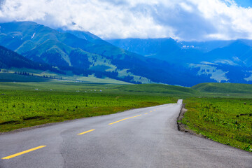 Empty road and beautiful mountain with green grass in Nalati grassland,Xinjiang,China.