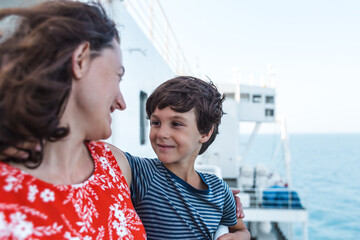 A boy and his mother stand on the deck of the ship and look at the sea.