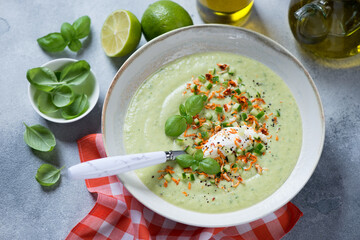 Plate of cold gazpacho made of cucumber and fresh green basil, horizontal shot on a light-blue stone background