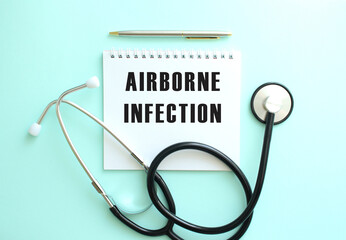 White notepad with the words AIRBORNE INFECTION and a stethoscope on a blue background.