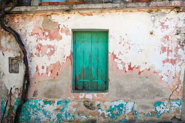 Wooden window shade and exfoliated wall paint on old façade in Kastelli Fournis, Crete, Greece