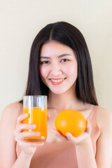 Beautiful beauty woman Asian cute girl feel happy drinking orange juice for good health in the morning , enjoying time in her home  white bedroom background - lifestyle beauty woman concept