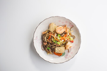 Japanese buckwheat soba noodles with shrimp and squid isolated on white background