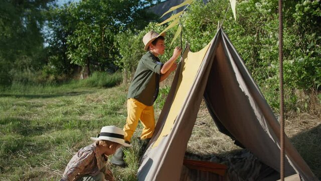 childrens relationship, adorable little boy helps his older brother build a wigwam while on a summer vacation in a village
