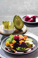Fresh fruit and vegetable salad with avocado, dragon fruit, pumpkin, tomato, radish, lettuce and corn salad. Concepts of healthy food, vegetarian and lifestyle trends.