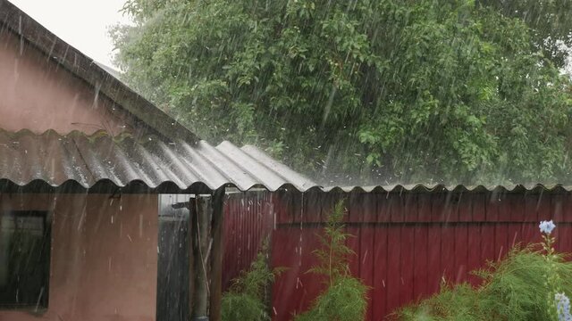 Heavy pouring rain with hail hits the roofs of houses, the hail bounces in different directions