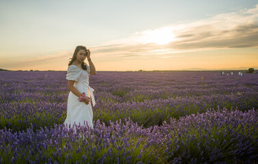 Fototapeta na wymiar outdoors romantic portrait of young happy and attractive woman in white summer dress enjoying carefree at beautiful lavender flowers field in travel and holiday concept