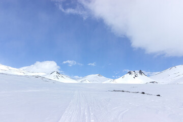 A long snow-covered road in the mountains. Volcanoes and rocks can be seen in the background....