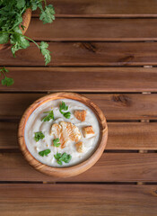 Cream soup with cauliflower, croutons and herbs on brown wooden table