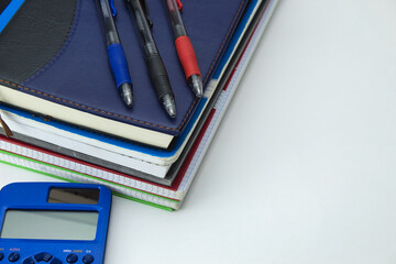 school tool set with notebooks, calculator, and colored pens ready for back to school on white background