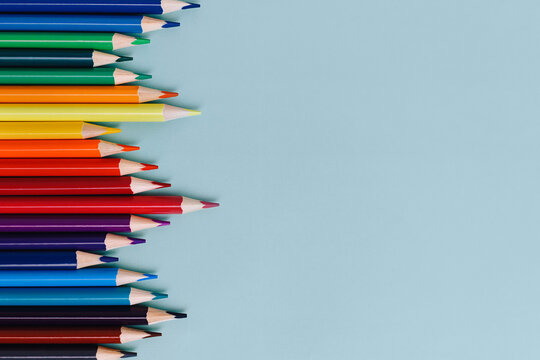Colored sharpened pencils lie on a blue background with space for copying. School supplies or school preparation. Top view.