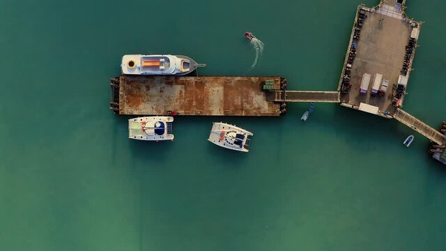 A catamaran with tourists is parked at the pier. Tourists in orange life jackets on a boat trip. The travel business is recovering from the coronavirus pandemic. Drone video top down bird eye view.